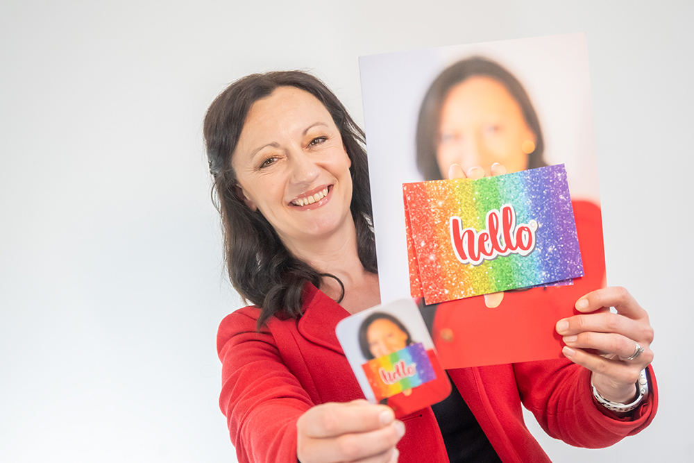 Yvonne is shown holding her business card and a brochure with the word 'Hello' on the front. Yvonne is smiling.
