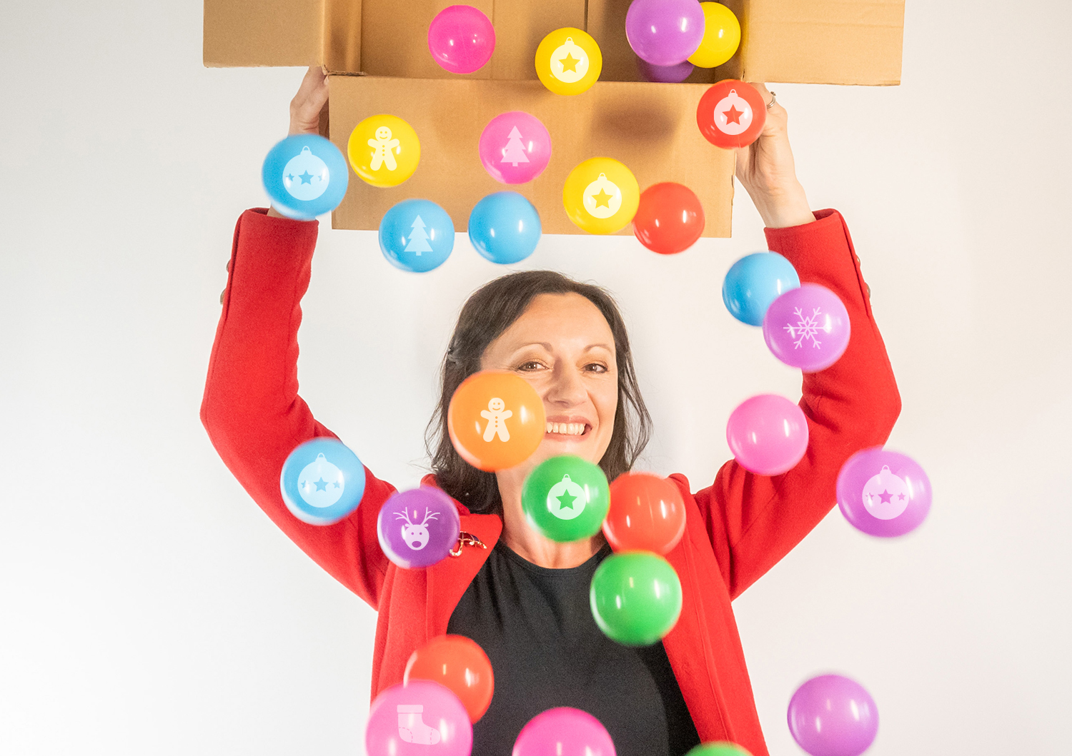 Yvonne is holding a box, tipping out lots of colourful baubles. Yvonne is smiling.